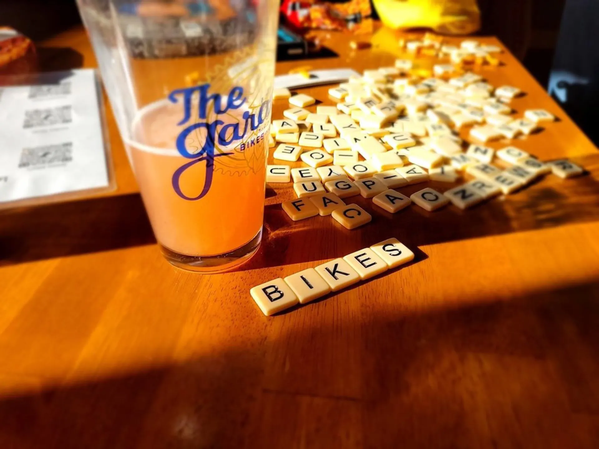Scrabble tiles spelling BIKES next to a Garage pint glass